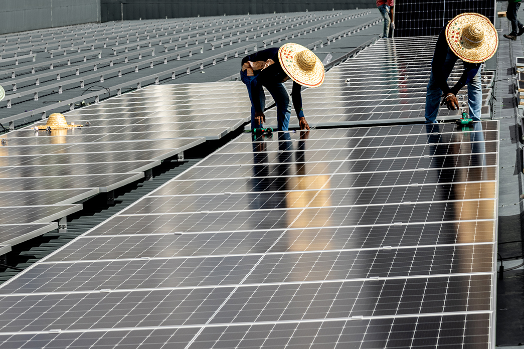 People with straw hats working on a solar panel.