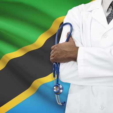 Doctor standing in front of a Tanzanian flag.