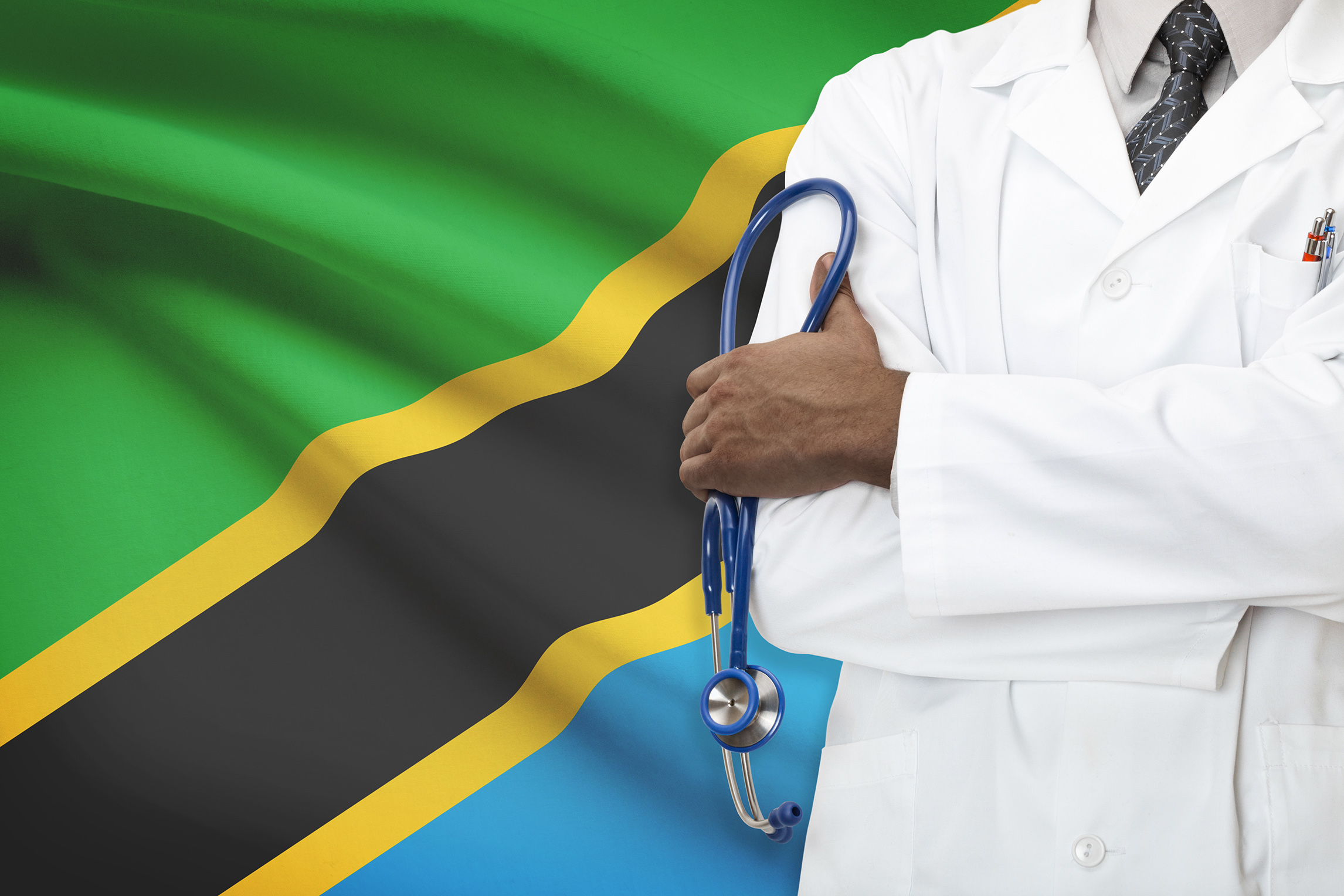 Doctor standing in front of Tanzanian flag.