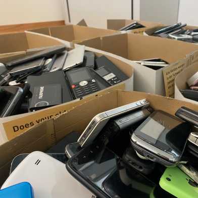 Several boxes full of old smartphones.
