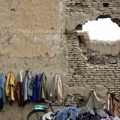 Afghan students' coats hanging on a destroyed wall.
