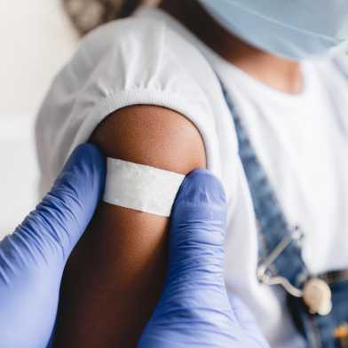 Close-up of a nurse applying a medical patch to a little girl after vaccination.